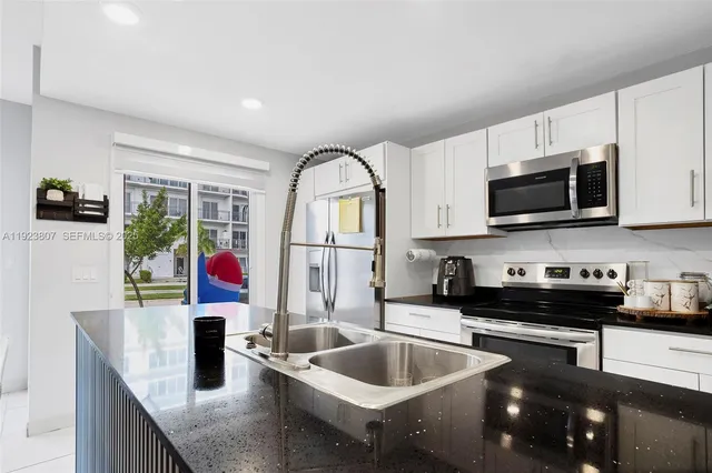 a kitchen with stainless steel appliances granite countertop a sink dishwasher stove and microwave with wooden floor
