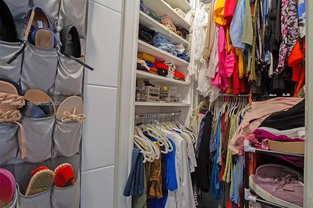a view of walk in closet with clothes and shoes