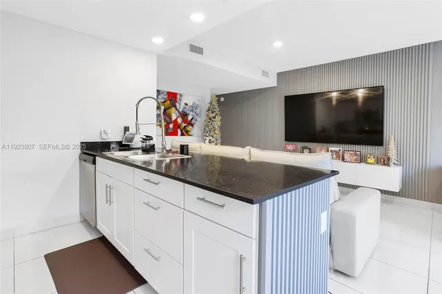a kitchen with granite countertop a sink and a flat screen tv