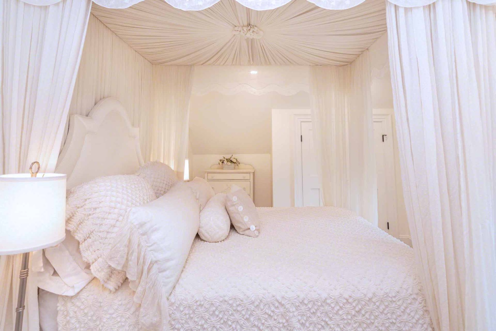 16 Mill Street Edgartown, MA 02539 - Photo 26 of 42 a bedroom with a large bed and a chandelier