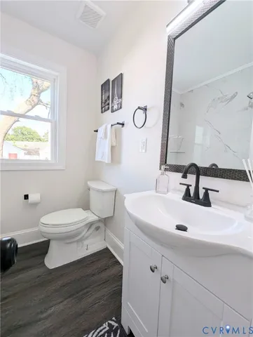 a bathroom with a sink mirror toilet and next to a window