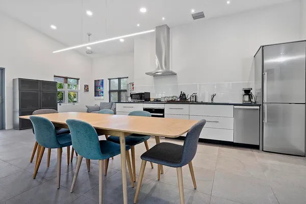 a kitchen with stainless steel appliances kitchen island granite countertop a table chairs in it and white cabinets