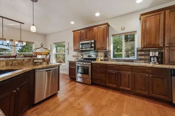 a kitchen with stainless steel appliances granite countertop a refrigerator a oven and a sink with cabinets