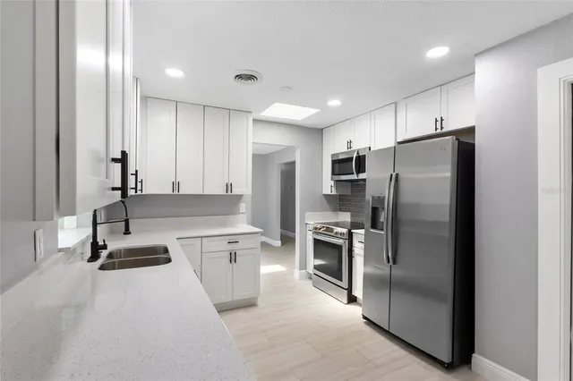 a kitchen with stainless steel appliances granite countertop a refrigerator and a sink