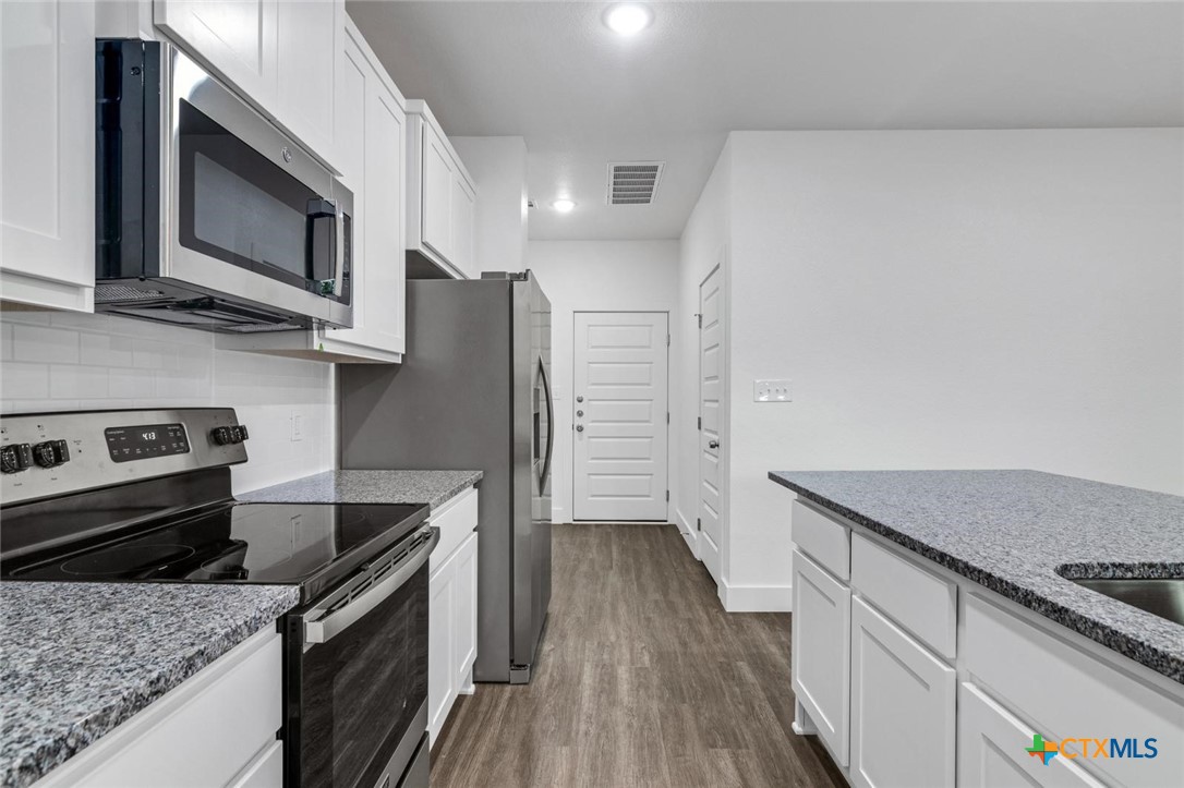 1904 Royal Loop Belton, TX 76513 - Photo 7 of 13 a kitchen with stainless steel appliances granite countertop a stove a refrigerator and a microwave