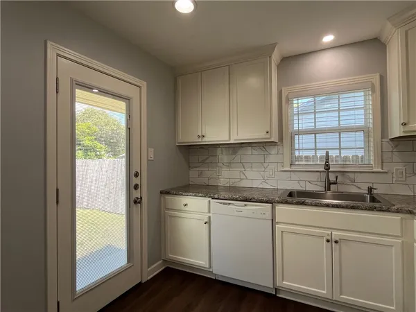 a kitchen with white cabinets and a window