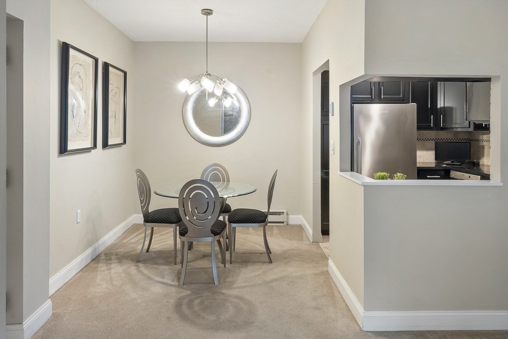 31 Hamlin Lane, Unit B11 Needham, MA 02492 - Photo 8 of 12 a kitchen with stainless steel appliances granite countertop a refrigerator a stove a dining table and chairs
