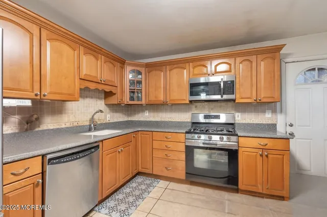 a kitchen with stainless steel appliances granite countertop a stove a sink dishwasher and a refrigerator