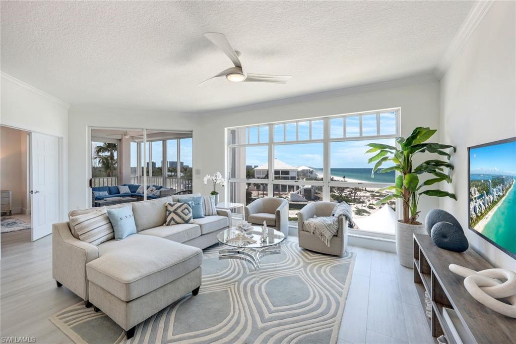 269 Barefoot Beach Boulevard, Unit 403 Bonita Springs, FL 34134 - Photo 2 of 27 Living area featuring a textured ceiling, ornamental molding, ceiling fan, and wood finished floors