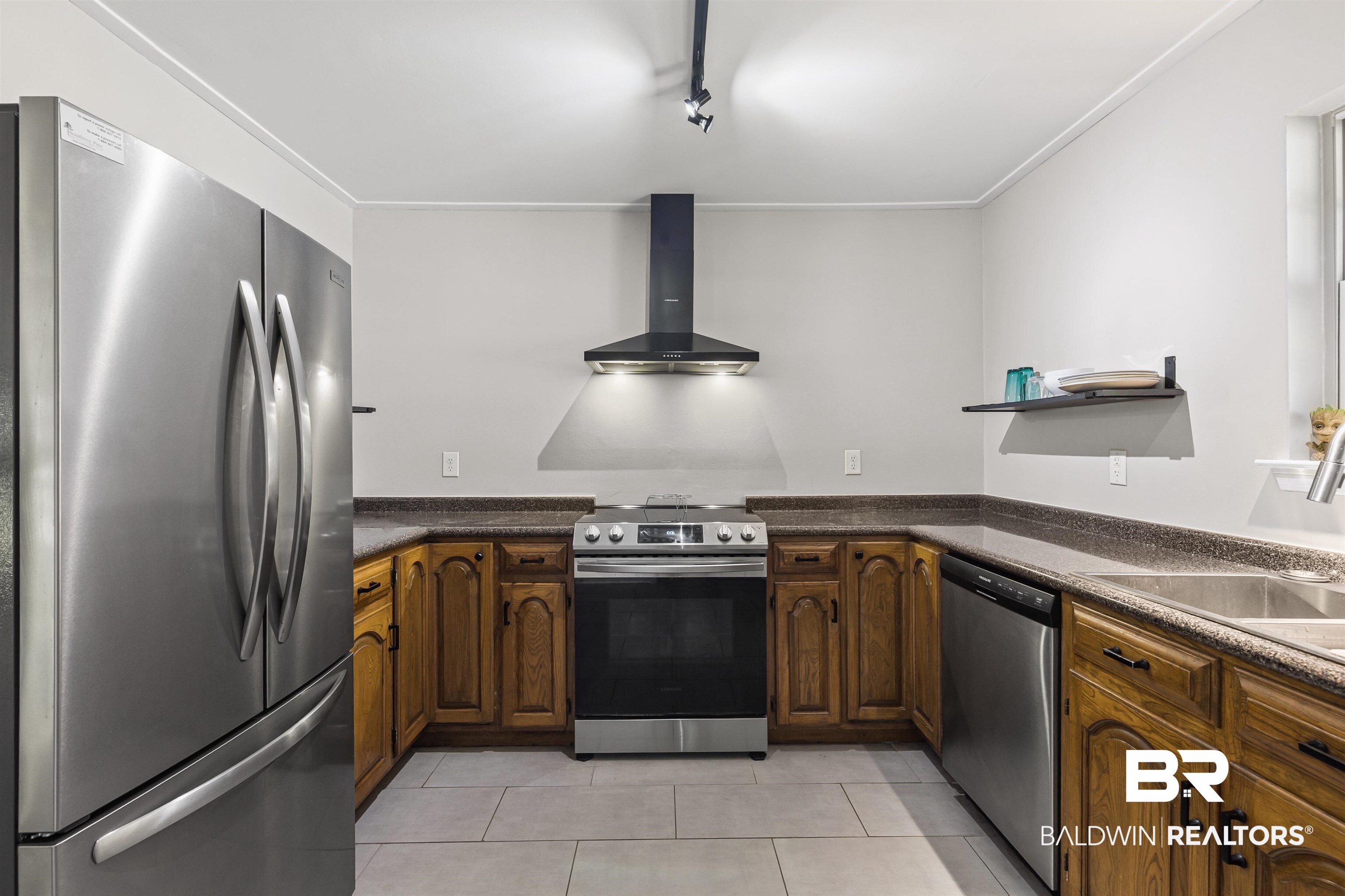 8911 Owassa Road Evergreen, AL 36401 - Photo 3 of 24 Kitchen with stainless steel appliances, wall chimney range hood, light tile patterned floors, open shelves, and track lighting