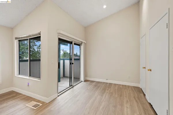 an empty room with wooden floor and windows