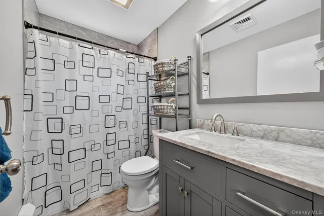 a bathroom with a granite countertop toilet and a sink
