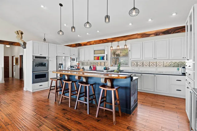 a kitchen with stainless steel appliances granite countertop a refrigerator a stove top oven a sink dishwasher and white cabinets with wooden floor