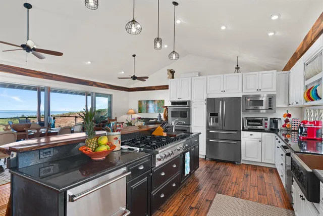 a kitchen with a sink stainless steel appliances and wooden floor