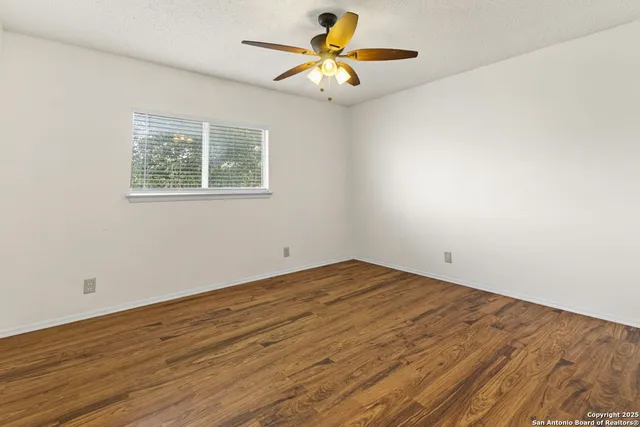 a view of a room with wooden floor and a chandelier fan