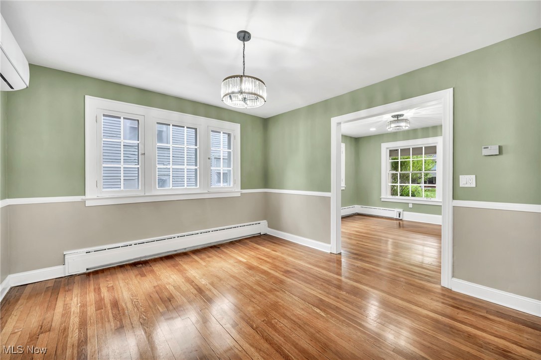 2980 East Overlook Road Cleveland, OH 44118 - Photo 11 of 49 Unfurnished room featuring hardwood / wood-style flooring, a notable chandelier, a baseboard heating unit, and a wall mounted air conditioner