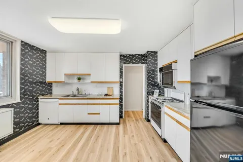 a kitchen with stainless steel appliances a sink wooden floor and a refrigerator