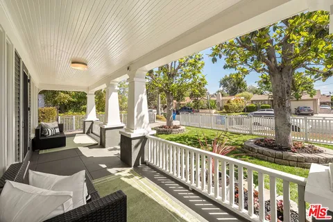 a view of a porch with couches potted plants and large tree