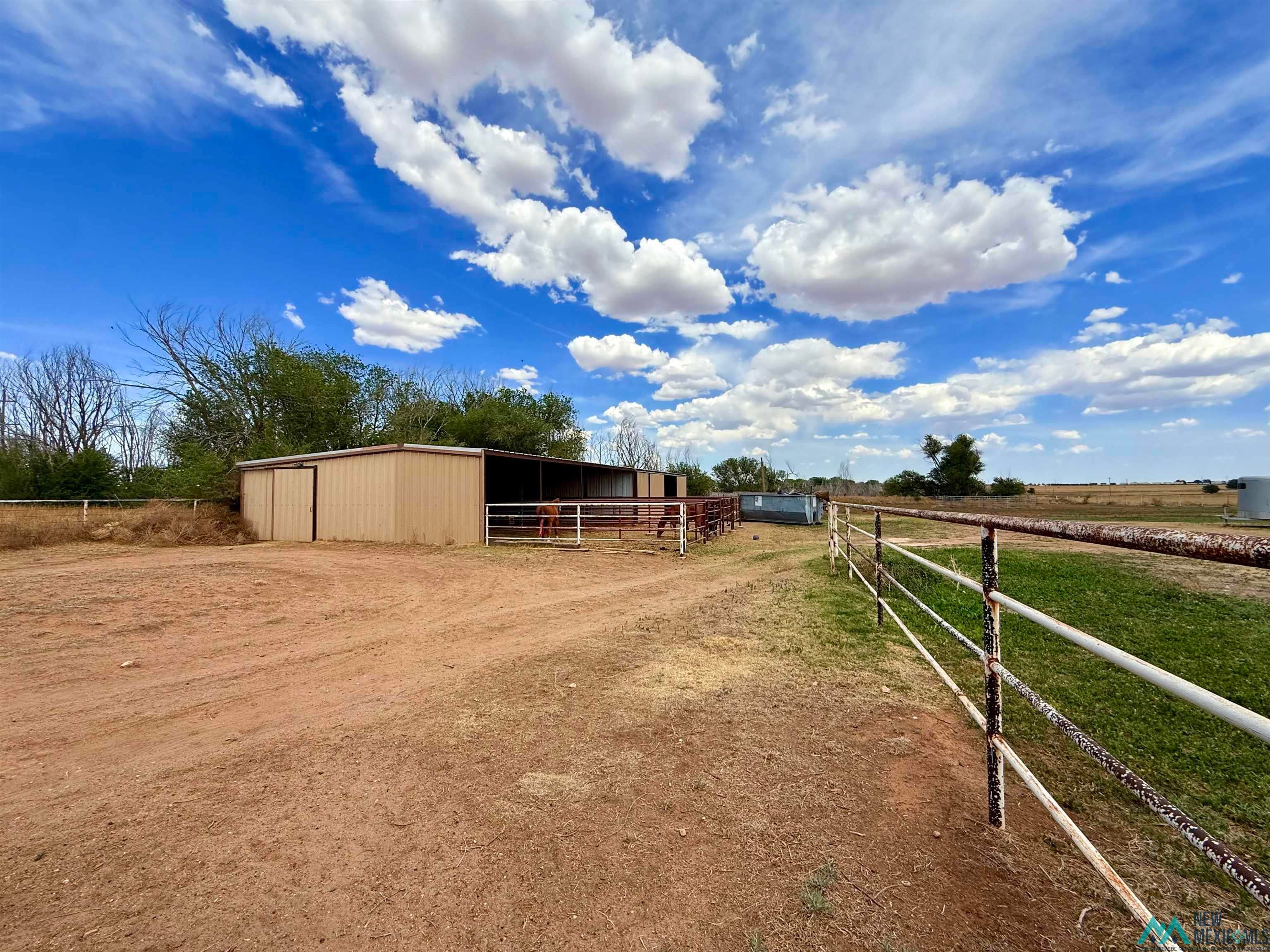 997 State Rte 108 Texico, NM 88135 - Photo 23 of 33 Metal-sided barn with an open-air extension, featuring a fenced corral area and additional metal fencing