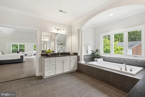 a large white bathroom with a large tub sink and mirror