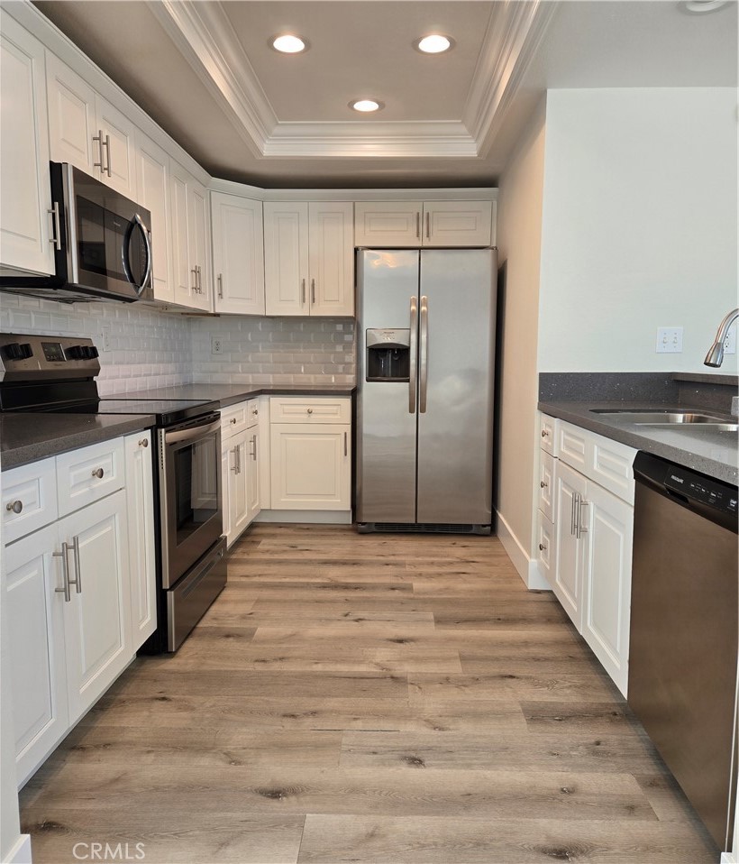 a kitchen with stainless steel appliances granite countertop a stove top oven a refrigerator a sink and dishwasher with wooden floor