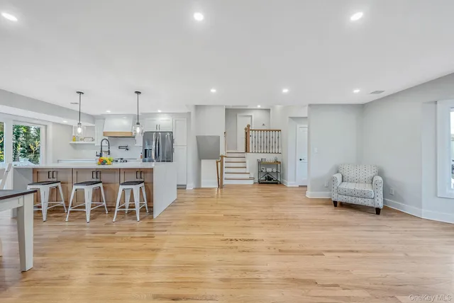 a view of kitchen with kitchen island a dining table chairs sink and white cabinets