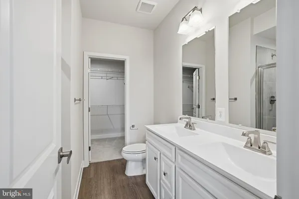 a bathroom with a double vanity sink a toilet and a shower