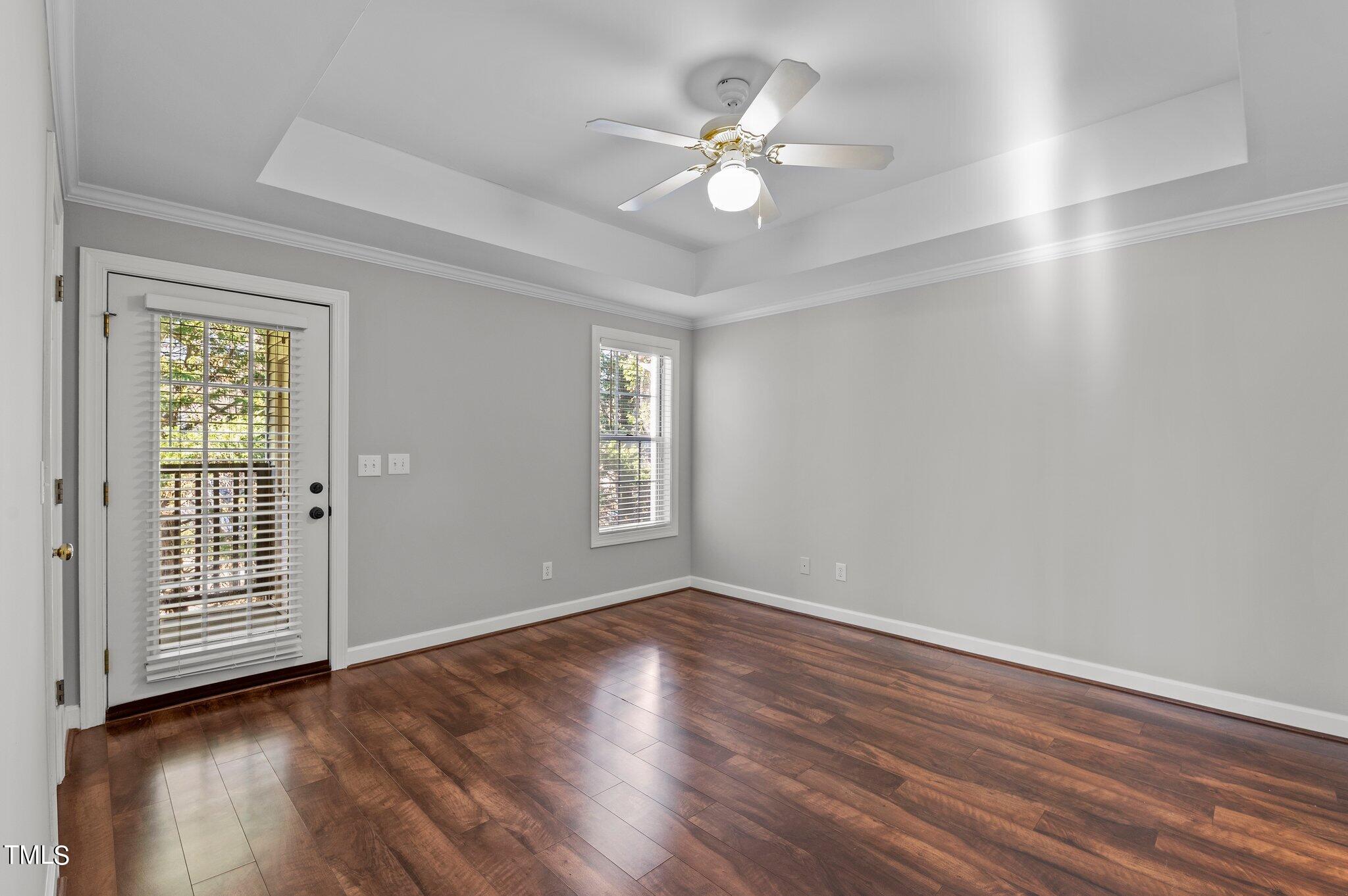 7018 Sandy Forks Road, Unit 302 Raleigh, NC 27615 - Photo 11 of 28 an empty room with wooden floor chandelier fan and windows