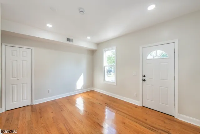 a view of empty room with wooden floor and fan