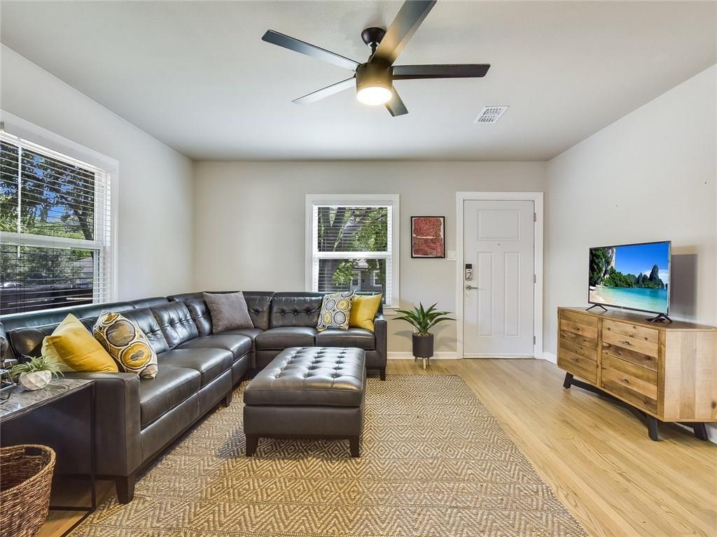3304 Robinson Avenue, Unit 1 Austin, TX 78722 - Photo 6 of 13 Bright, fully furnished living room with hardwood floors, modern furnishings, ceiling fan, and abundant natural light—designed for turnkey Central Austin living.