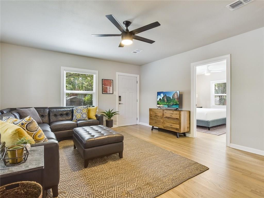 3304 Robinson Avenue, Unit 1 Austin, TX 78722 - Photo 7 of 13 Bright, fully furnished living room with hardwood floors, modern furnishings, ceiling fan, and natural light—designed for turnkey Central Austin living.