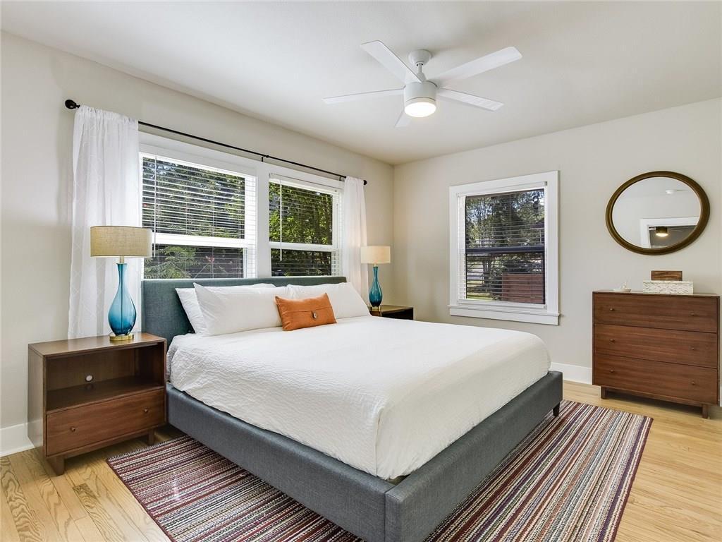 3304 Robinson Avenue, Unit 1 Austin, TX 78722 - Photo 8 of 13 Spacious primary bedroom featuring a king bed, hardwood floors, ceiling fan, and abundant natural light—ideal for long-term comfort.
