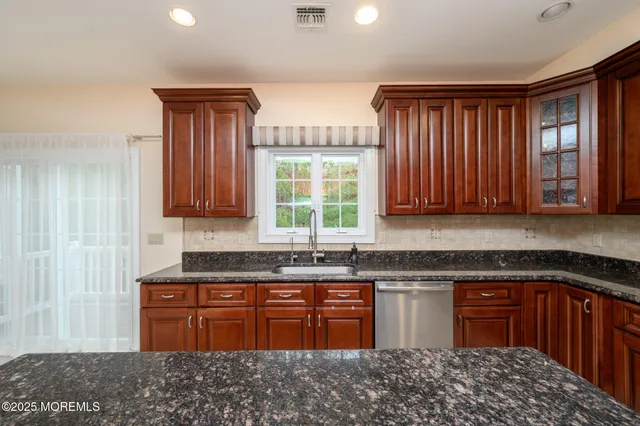 a kitchen with stainless steel appliances granite countertop wooden cabinets a stove a sink and dishwasher