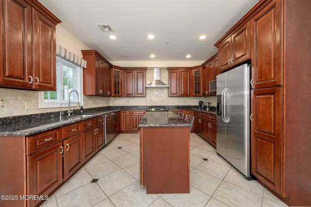 a large kitchen with stainless steel appliances granite countertop a refrigerator and a sink