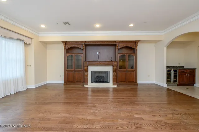 a view of an empty room with wooden floor fireplace and a window