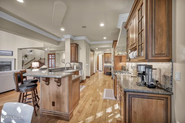 a large hall with stainless steel appliances kitchen island granite countertop a sink and cabinets