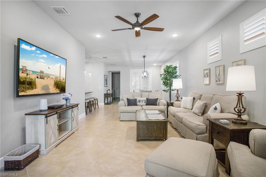 7674 Jacaranda Lane Naples, FL 34114 - Photo 4 of 45 a living room with furniture a flat screen tv and kitchen view