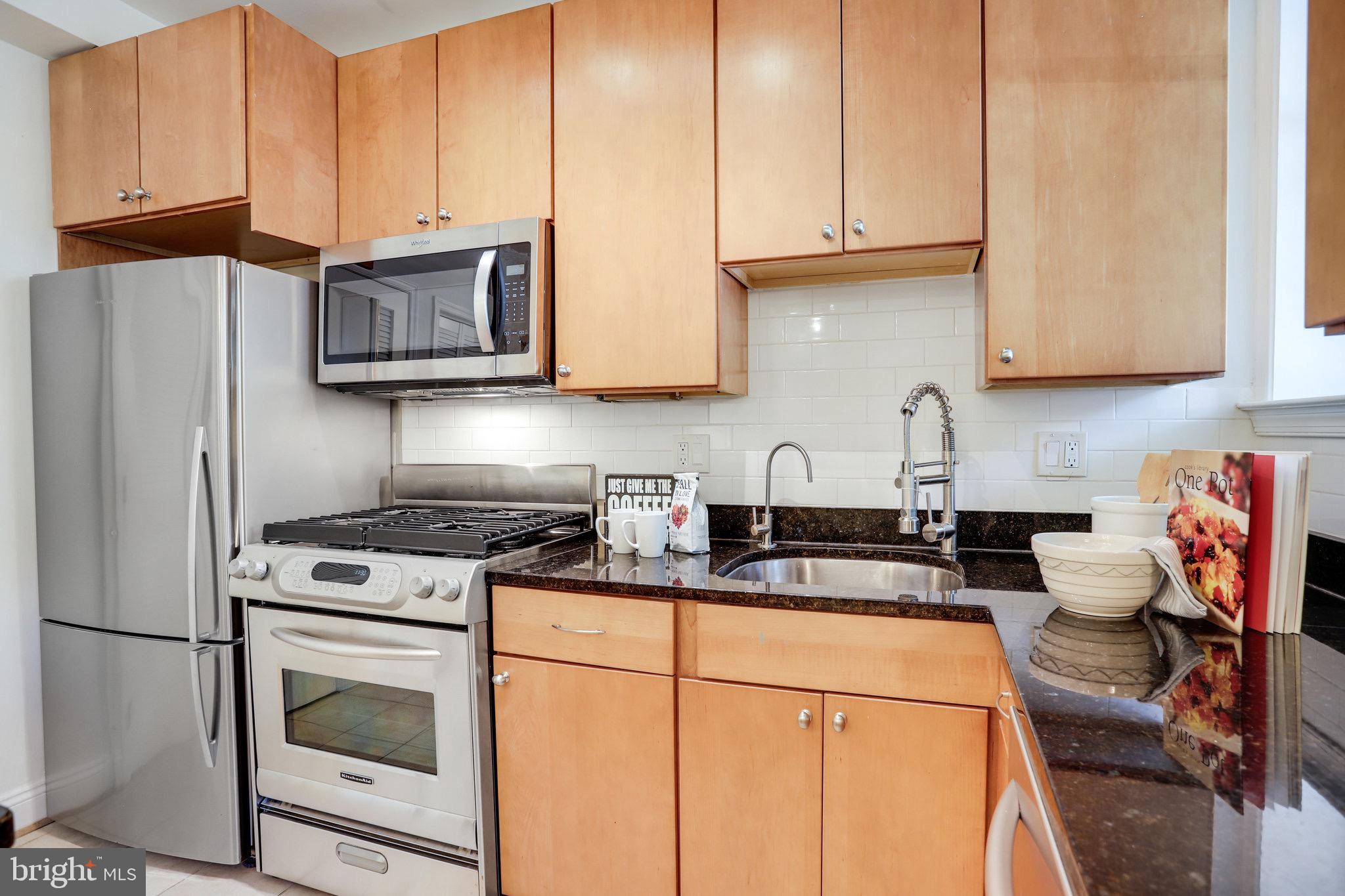 1438 Columbia Road Northwest, Unit 101 Washington, DC 20009 - Photo 16 of 39 a kitchen with granite countertop a sink stainless steel appliances and white cabinets