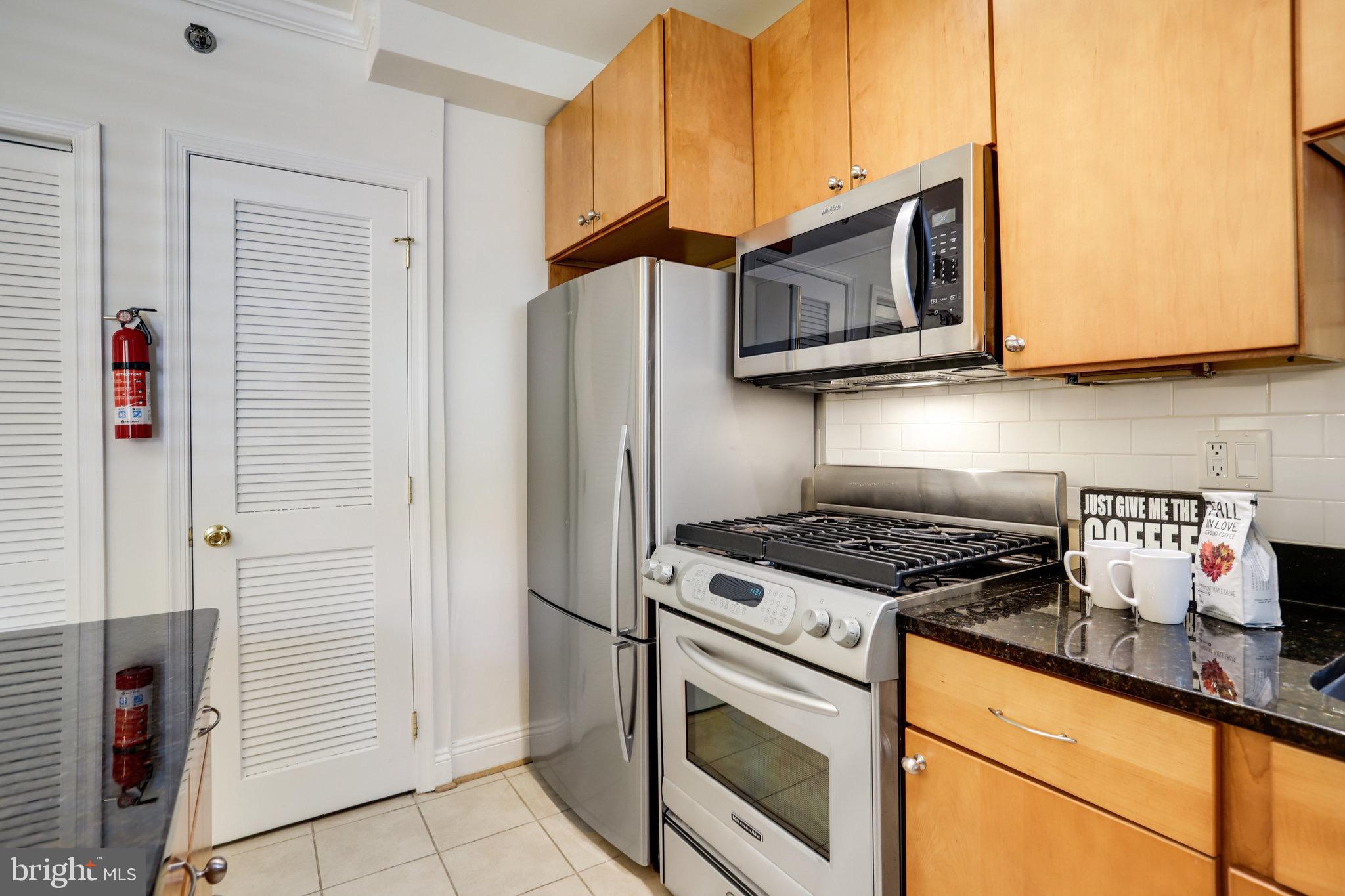1438 Columbia Road Northwest, Unit 101 Washington, DC 20009 - Photo 17 of 39 a kitchen with stainless steel appliances granite countertop a stove a sink and a microwave