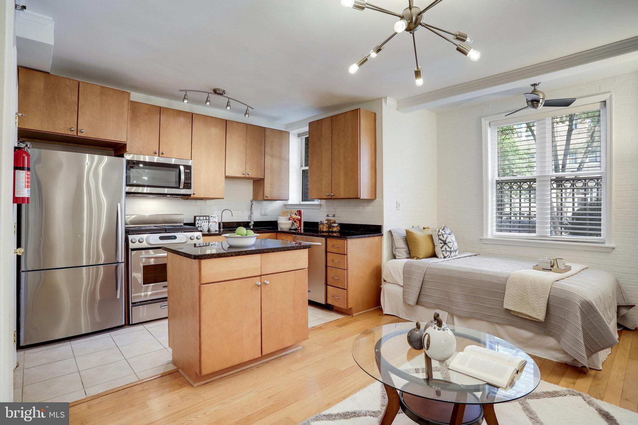 1438 Columbia Road Northwest, Unit 101 Washington, DC 20009 - Photo 3 of 39 a kitchen with stainless steel appliances granite countertop a refrigerator a stove a sink a dining table and chairs with wooden floor