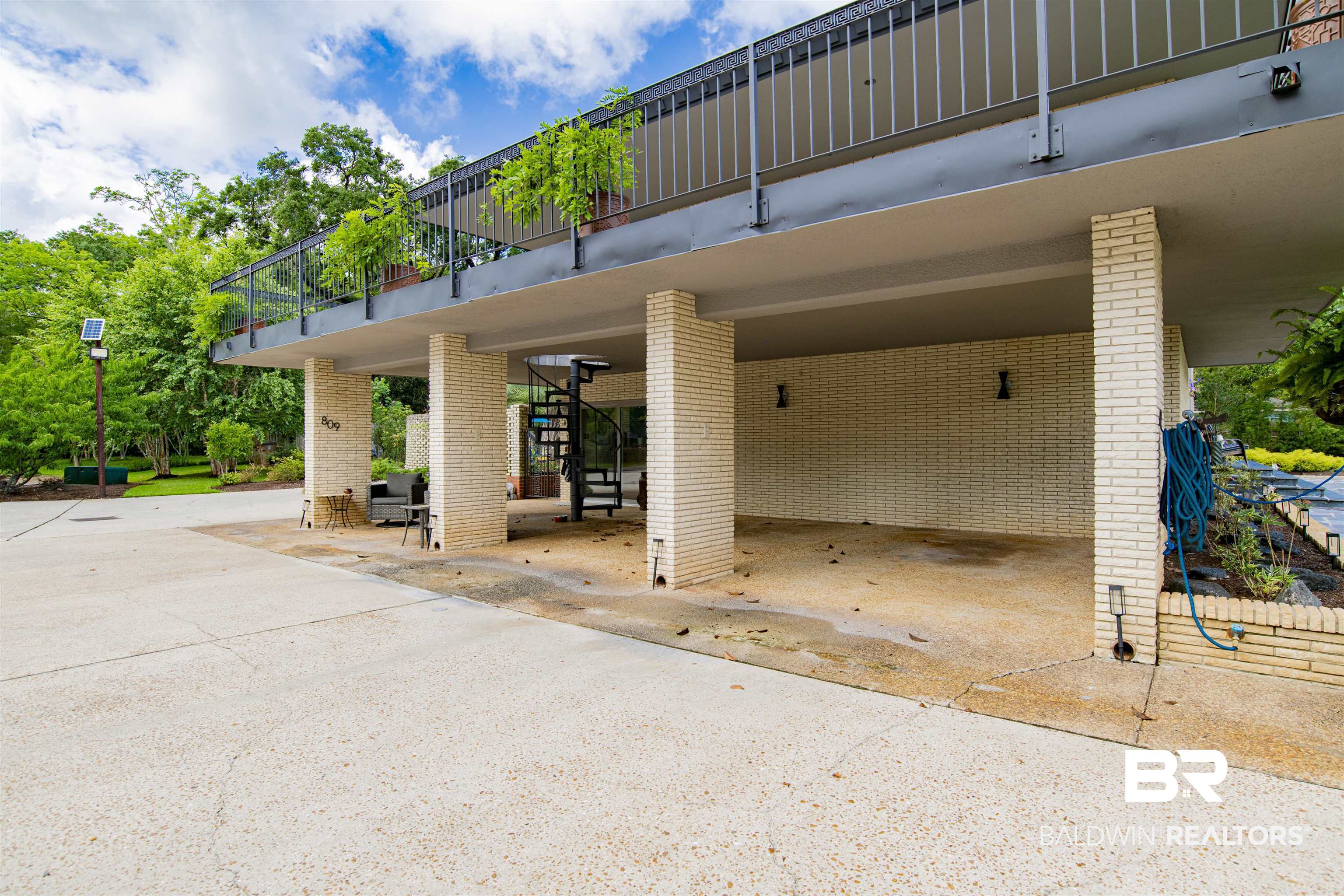 809 Bernard Circle Mobile, AL 36693 - Photo 72 of 75 Covered parking area featuring a concrete drive, light brick columns, and a spiral staircase providing exterior access to the upper level