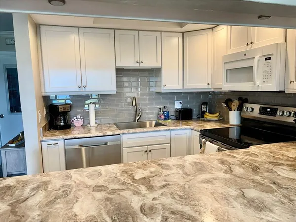 a kitchen with stainless steel appliances kitchen island granite countertop a refrigerator sink and cabinets