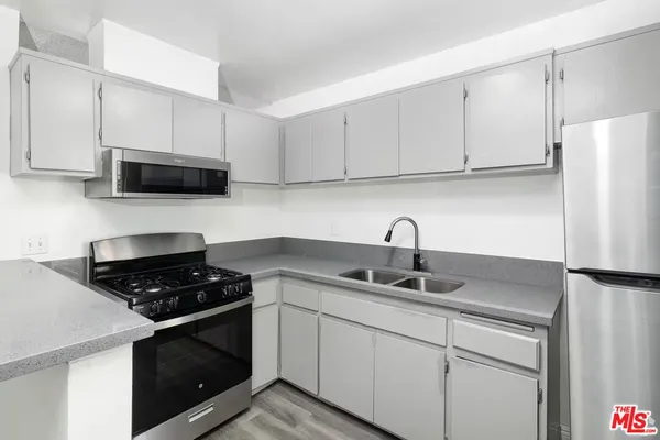 a kitchen with stainless steel appliances granite countertop white cabinets a stove a sink and a refrigerator