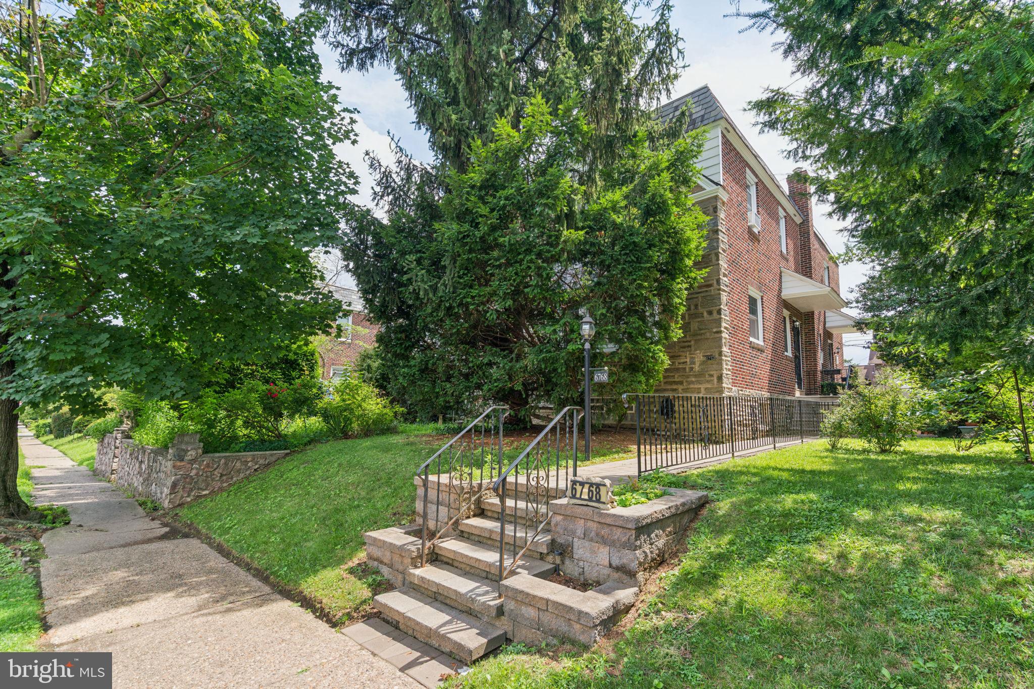 a front view of a house with garden and trees