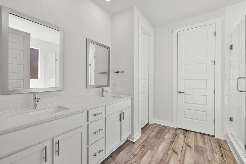 113 Shadow Oak Cove Georgetown, TX 78628 - Photo 21 of 40 A well-lit primary bathroom features a dual vanity with white cabinets and wood-inspired flooring.