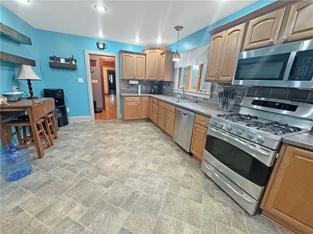 a kitchen with stainless steel appliances granite countertop a stove top oven a sink dishwasher and a refrigerator
