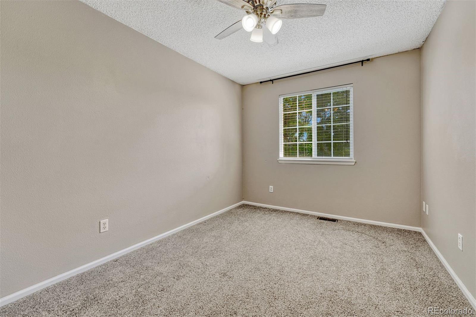 4927 Tarcoola Lane Highlands Ranch, CO 80130 - Photo 16 of 30 an empty room with a chandelier fan and windows