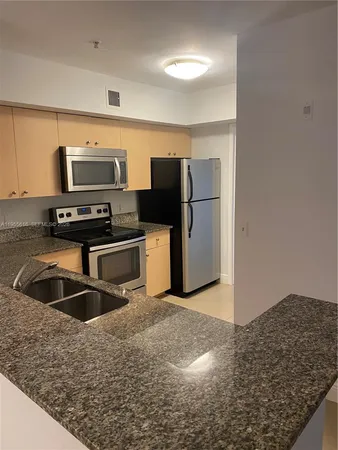a kitchen with stainless steel appliances granite countertop a refrigerator a stove and a sink