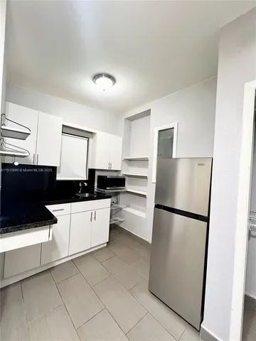 a kitchen with a refrigerator a stove top oven and white cabinets