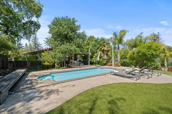 an aerial view of a house with backyard swimming pool and outdoor seating